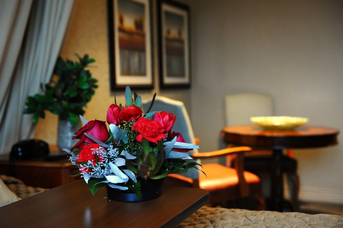 A cozy room with a vibrant red flower arrangement on a wooden table.