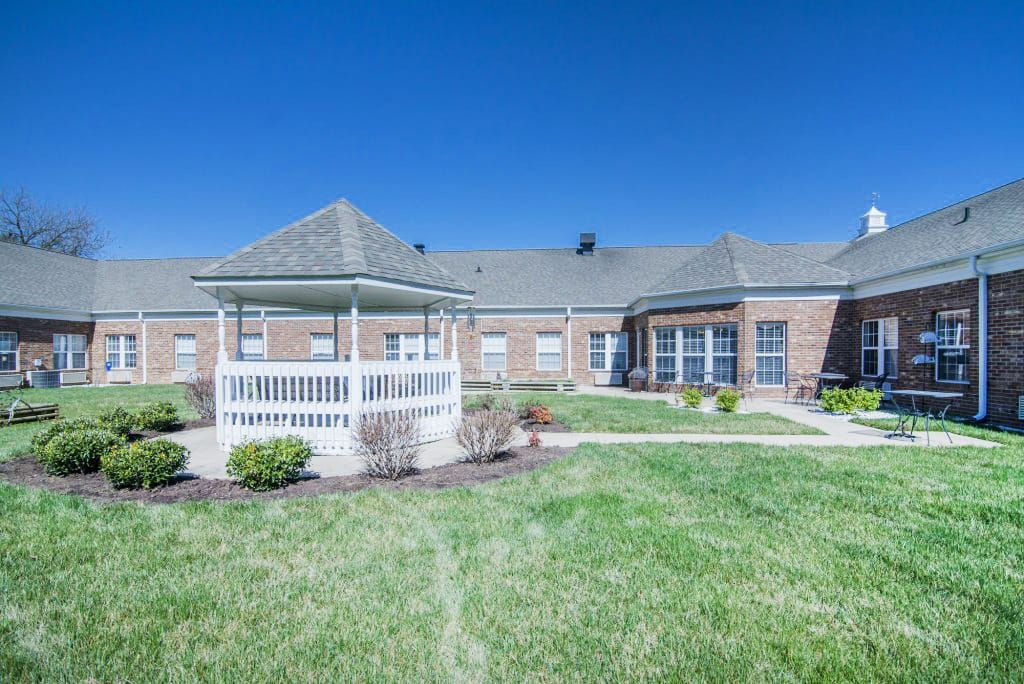 A sunny day view of a brick building with a gazebo and well-maintained lawn.