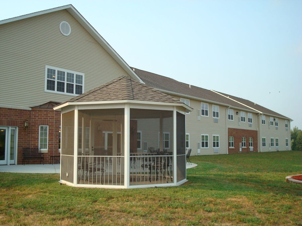 A residential building with a screened gazebo on a grassy lawn.