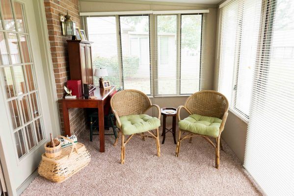 A cozy sunroom with wicker chairs and a small desk by the window.