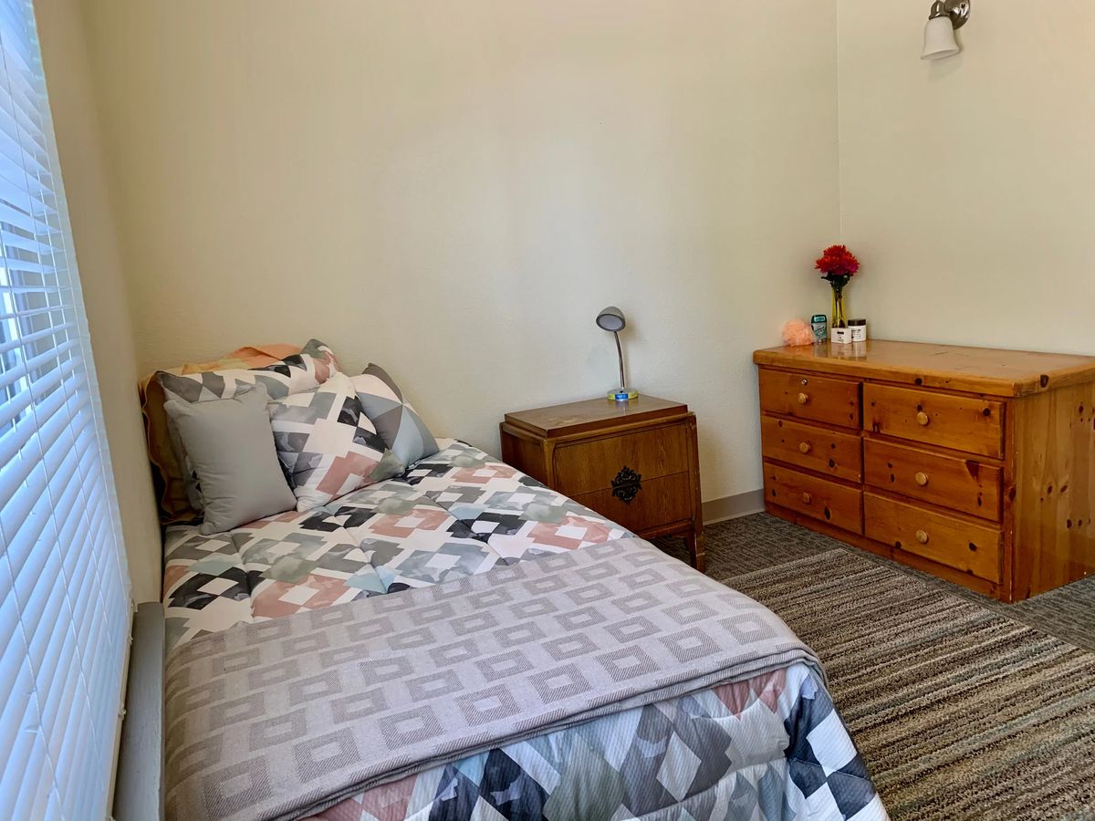 A minimalist bedroom with a single bed, dresser, and simple decor.