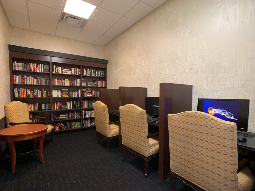 A quiet library space with bookshelves, computer stations, and comfortable chairs.