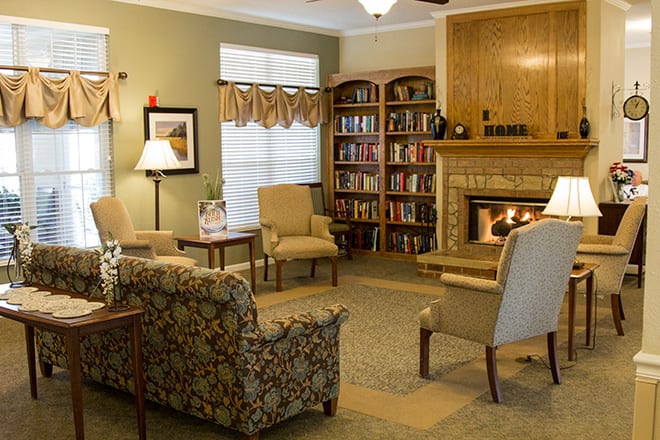 A cozy living room with a fireplace, bookshelves, and comfortable seating.