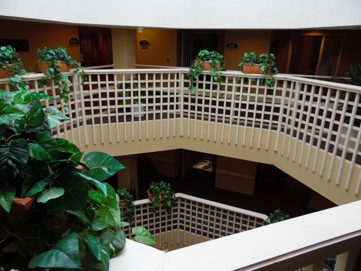 A multi-level atrium with indoor plants and a white railing.