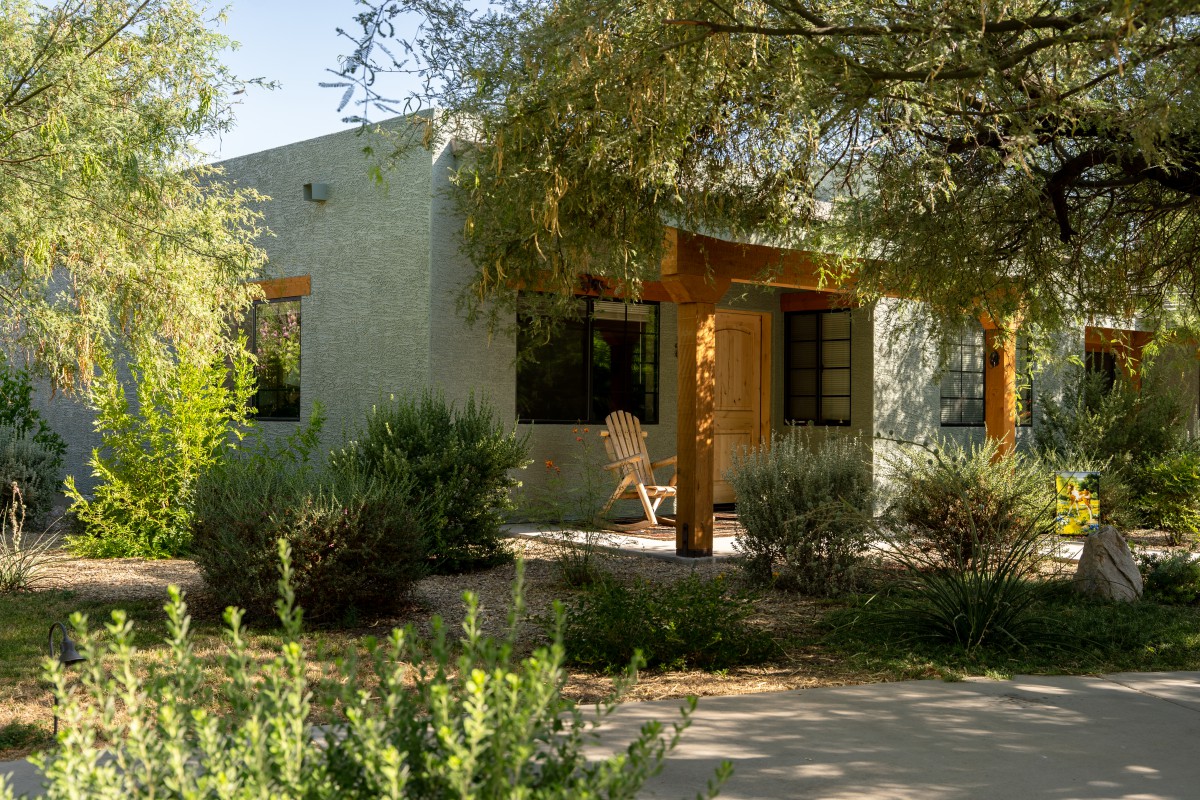A cozy house surrounded by lush greenery and bathed in sunlight.