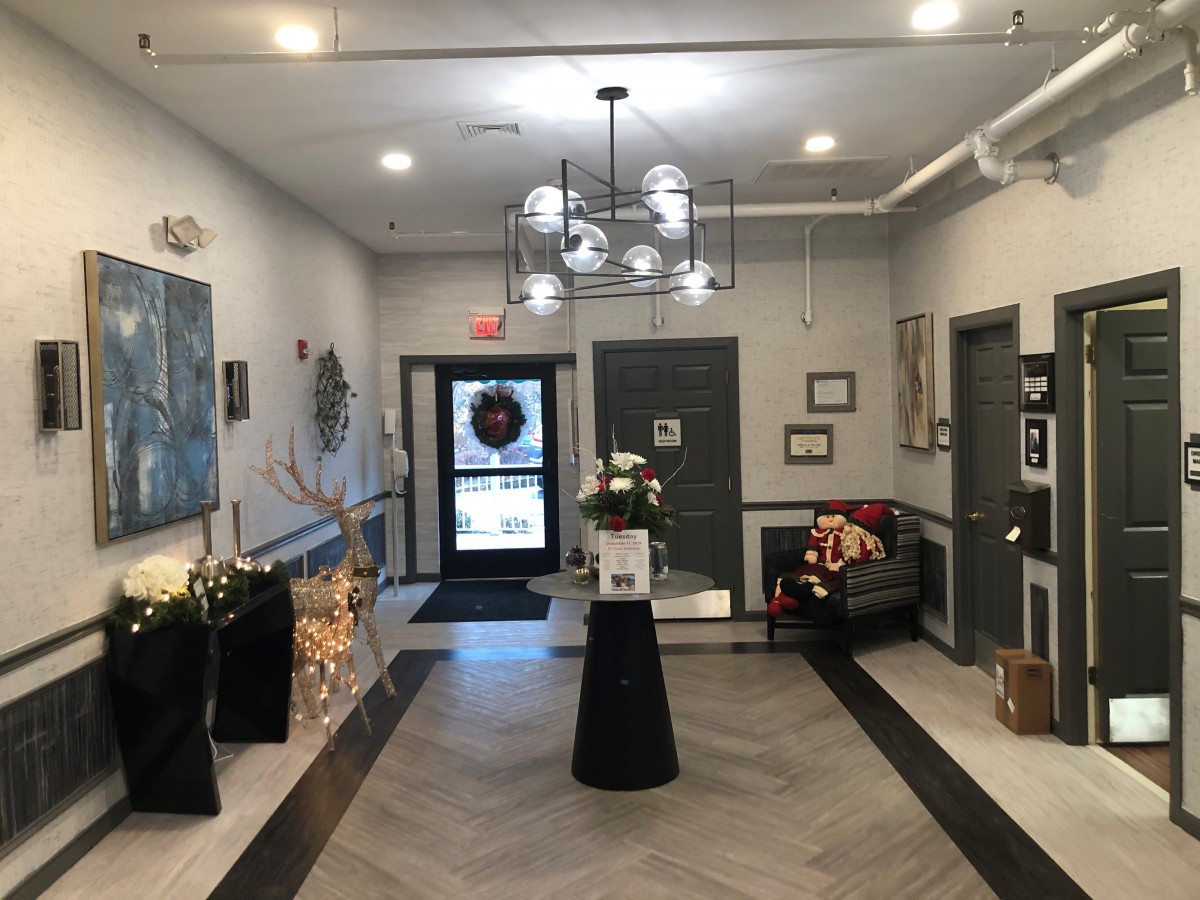A modern lobby with stylish decor, featuring a central floral arrangement, artwork on the walls, and a comfortable seating area.