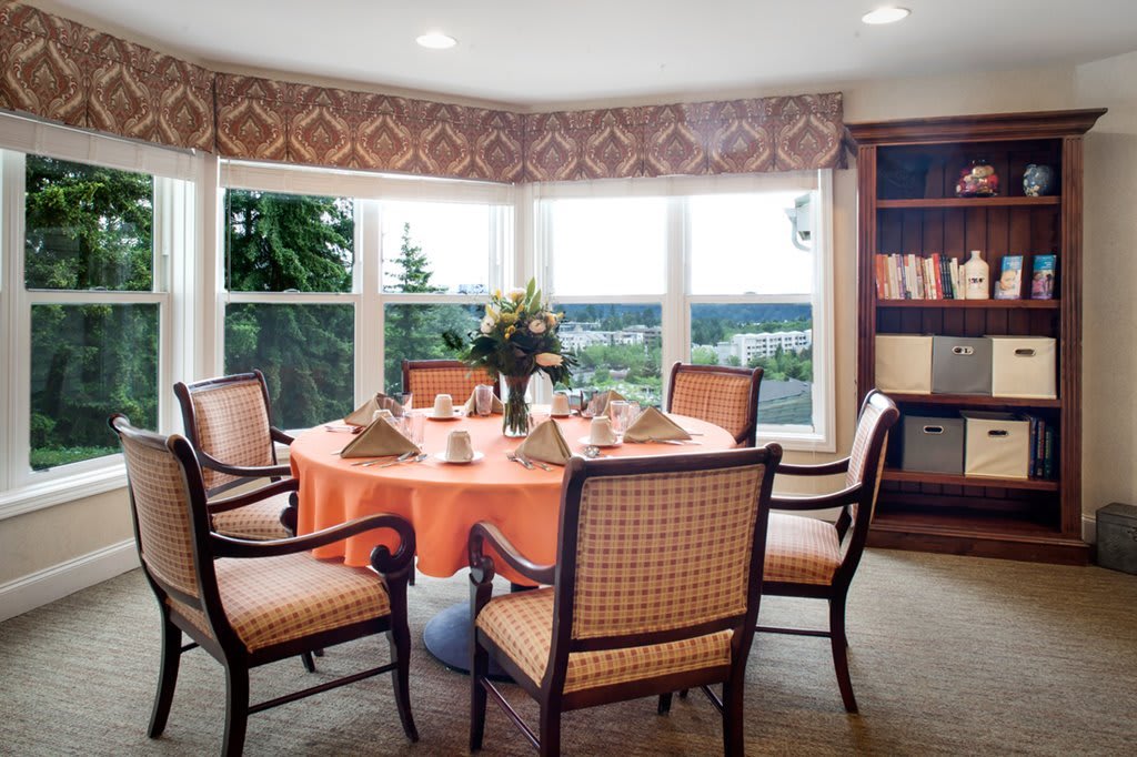 A beautifully set dining room table with a view through large windows, allowing natural light to illuminate the space.