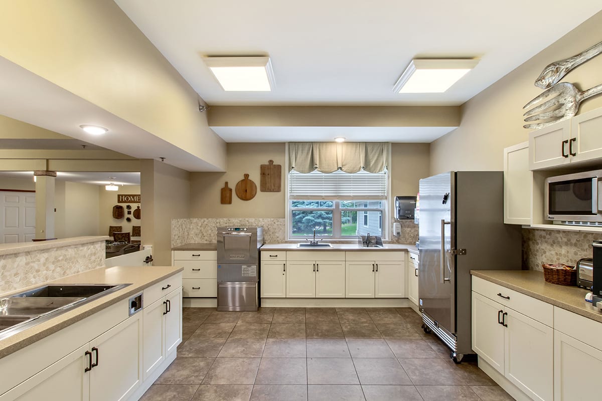 A spacious modern kitchen with stainless steel appliances and tiled flooring.