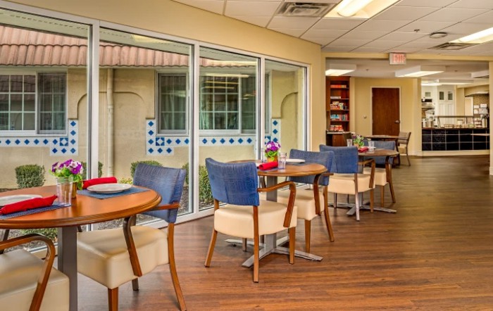 A modern dining area with tables and chairs adjacent to large windows.