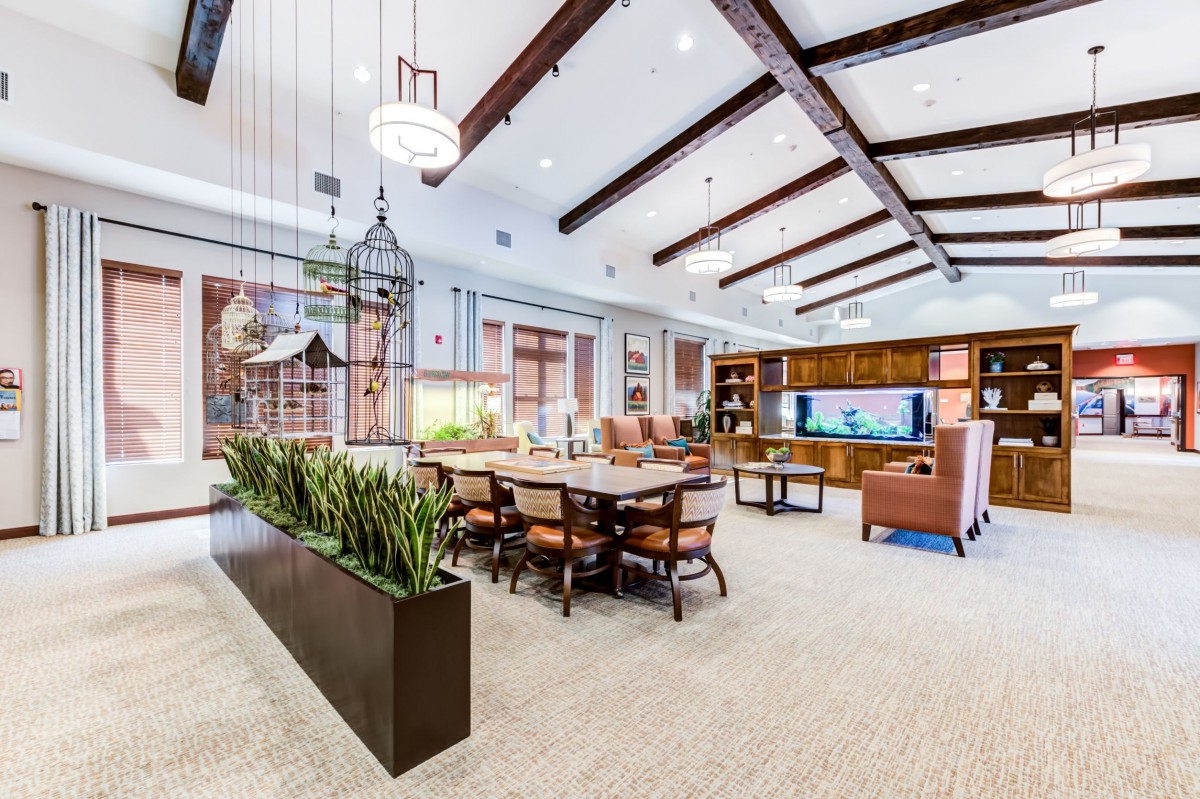 A spacious and modern living room with wooden beams, featuring a large dining table and comfortable seating area.