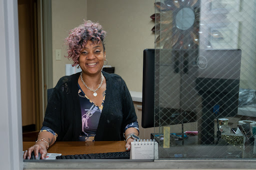 A cheerful woman at her desk in an office setting, ready to assist.
