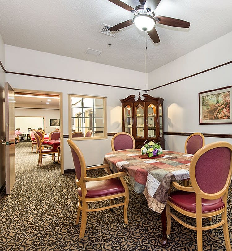 A cozy dining room with a table set for four, featuring upholstered chairs and a glass cabinet in the corner.