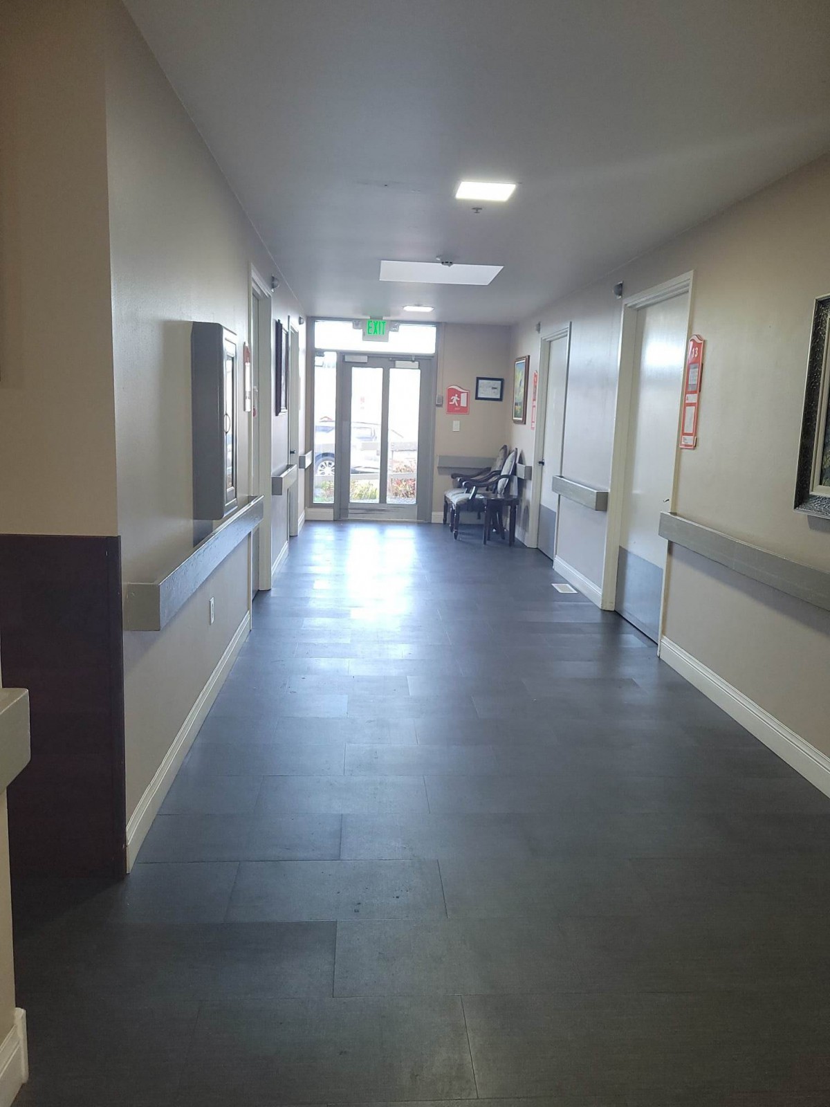 An empty hospital corridor leading to a set of doors.