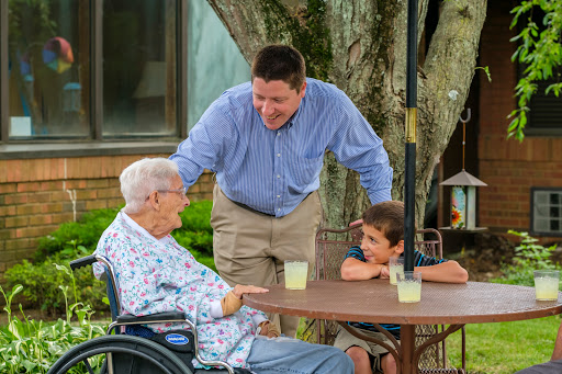A warm family moment as a man engages in conversation with an elderly woman and a young boy in a cozy outdoor setting.