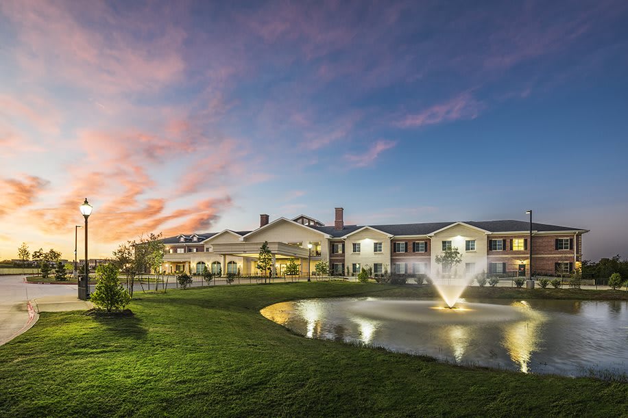 A beautiful building with a fountain in front, set against a stunning sunset backdrop.