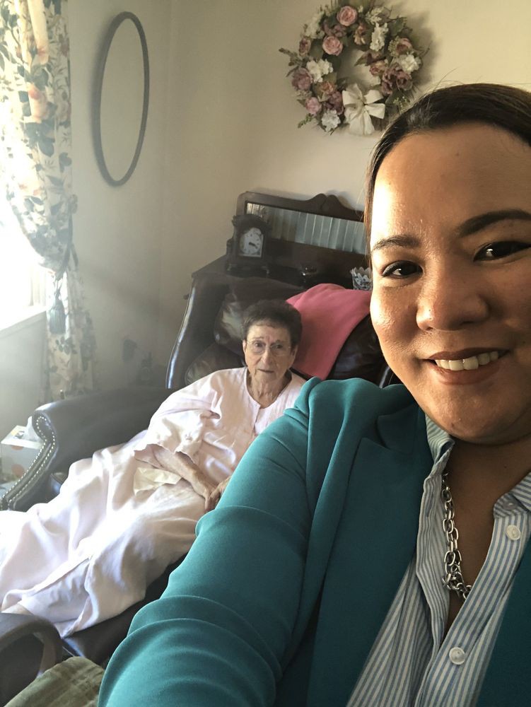 A person taking a selfie with someone relaxing in the background.