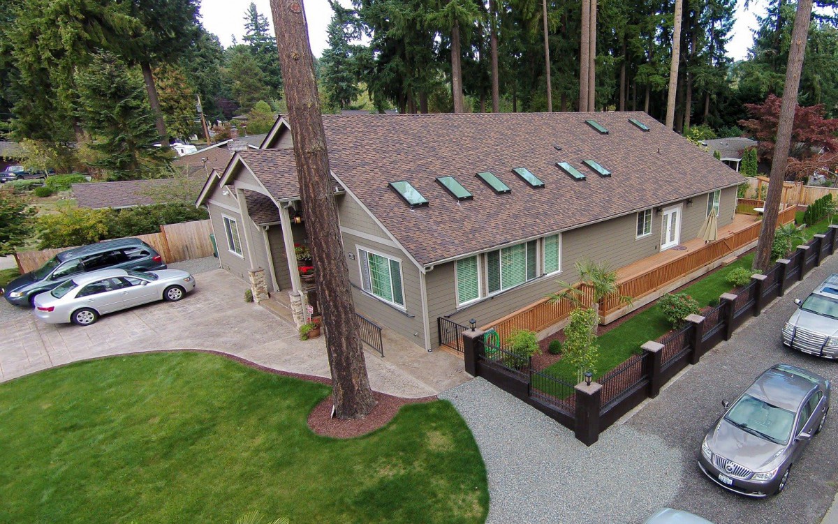 Aerial view of a suburban house with a well-maintained yard and surrounding trees.
