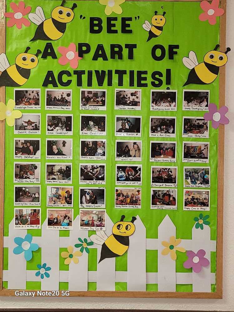 A vibrant bulletin board displaying photos of various activities, adorned with bee and flower decorations.
