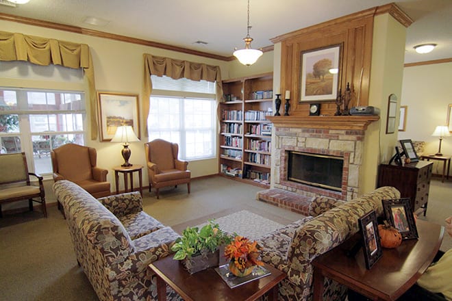 A cozy living room with a fireplace, comfortable seating, and a bookshelf.