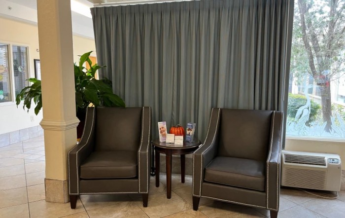 A cozy waiting area with two armchairs and a small table in front of curtains.