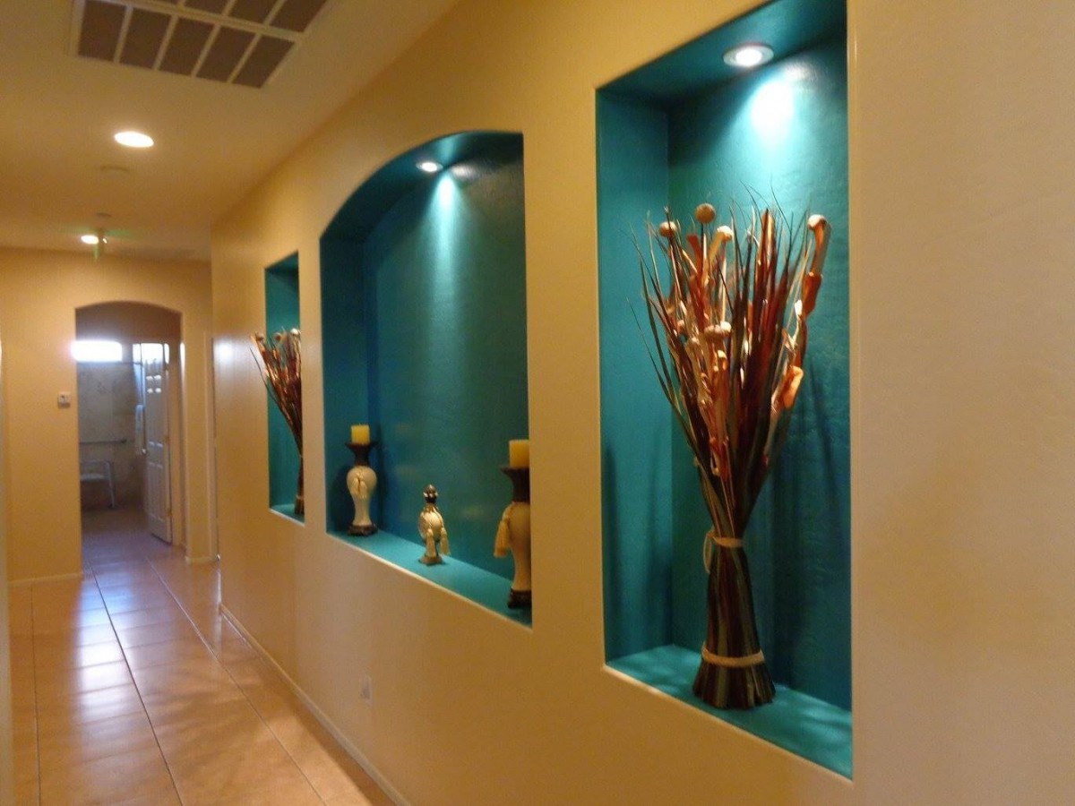 A hallway featuring beautifully lit wall niches with decorative vases, enhanced by recessed lighting.