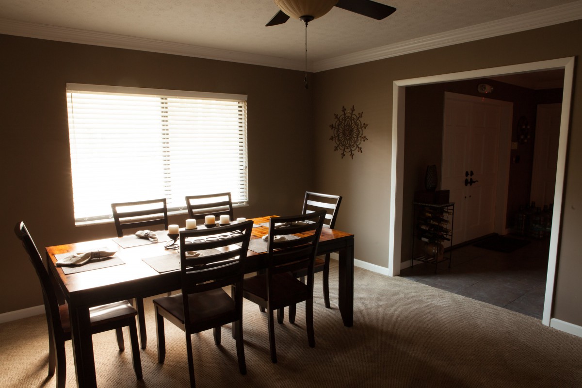 A cozy dining room with a wooden table, chairs, and natural light filtering through the window.