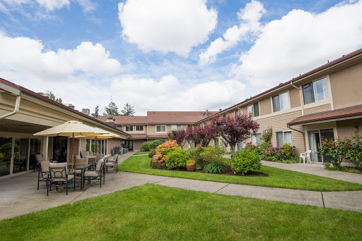 A tranquil courtyard with comfortable seating surrounded by vibrant plants and a picturesque sky.