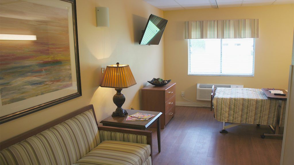A cozy hotel room with a television, lamp, and comfortable furnishings.