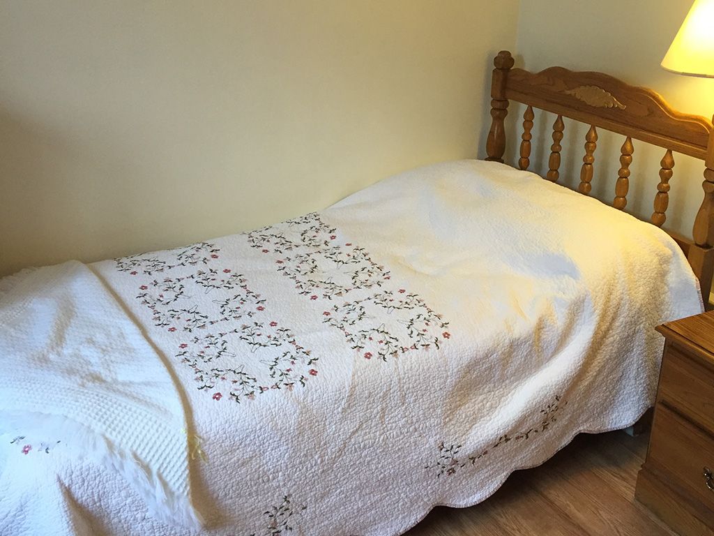 A neatly made single bed with a decorative quilt in a cozy room.