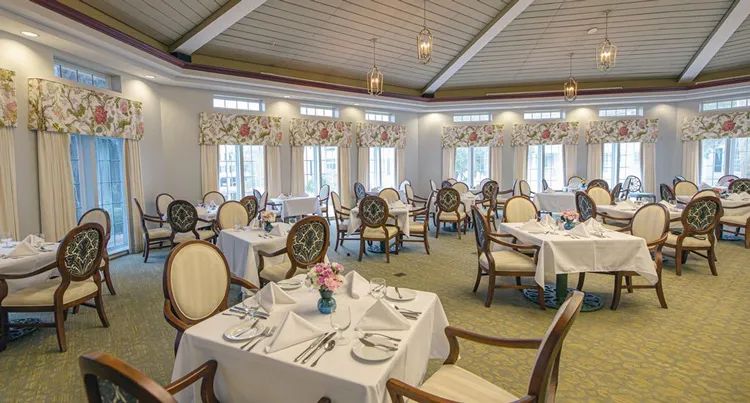 An elegant dining room with neatly arranged tables and chairs, featuring classic decor and bright lighting.