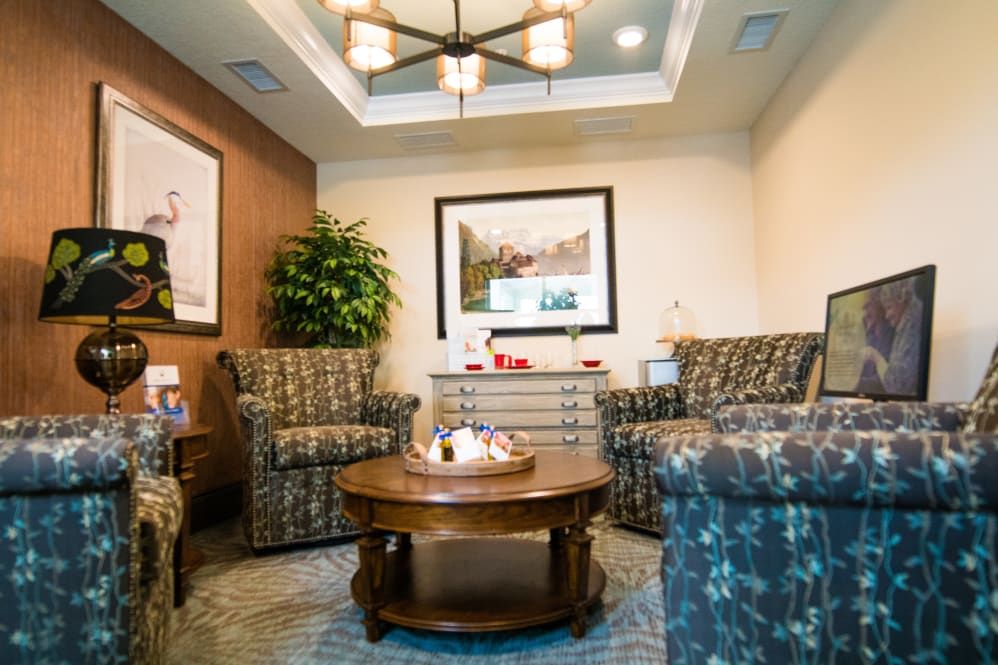 A cozy waiting room with comfortable chairs and a central table, adorned with plants and wall art.