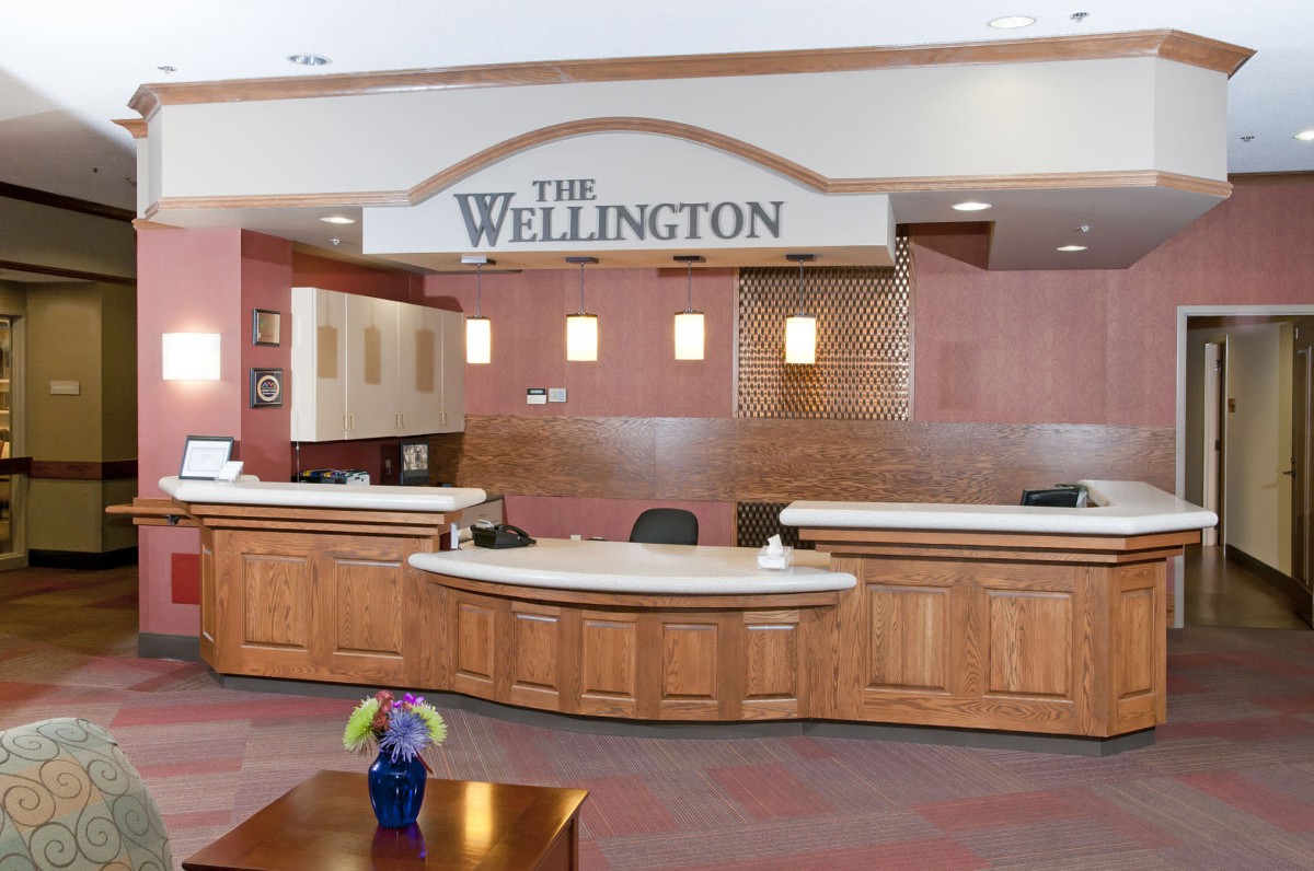 Reception area of The Wellington with wooden countertops and signage.