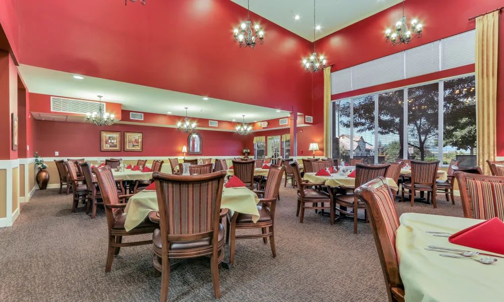 An elegant restaurant dining room with red walls and neatly arranged tables.