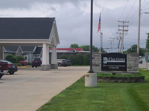 A view of a building with a sign indicating the establishment, along with a flag and surrounding greenery.