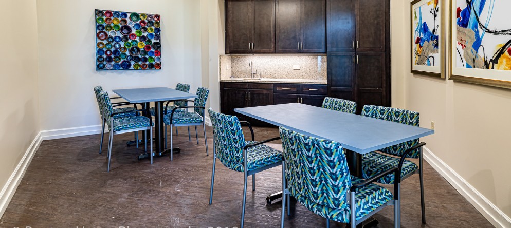 A modern conference room with tables, patterned chairs, and colorful artwork on the wall.