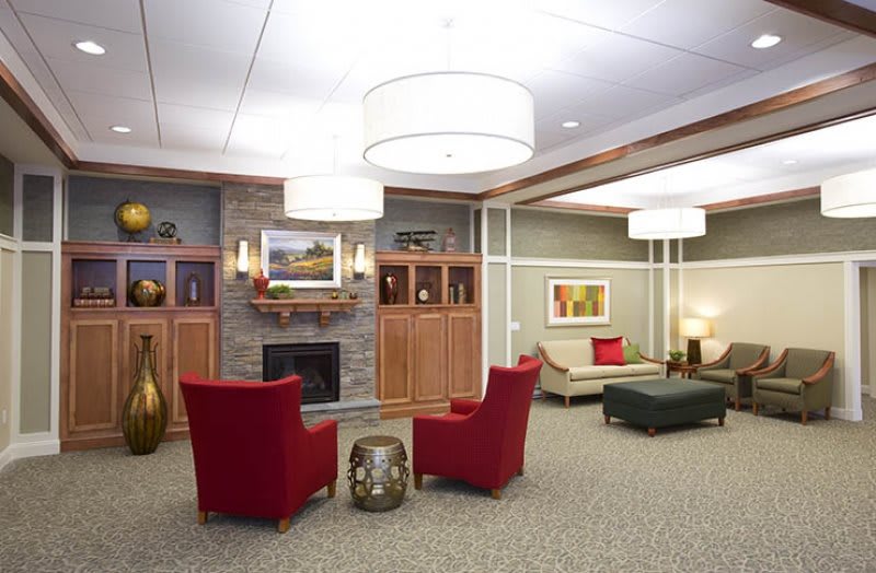 A cozy lobby area with red chairs, a fireplace, and elegant decor.