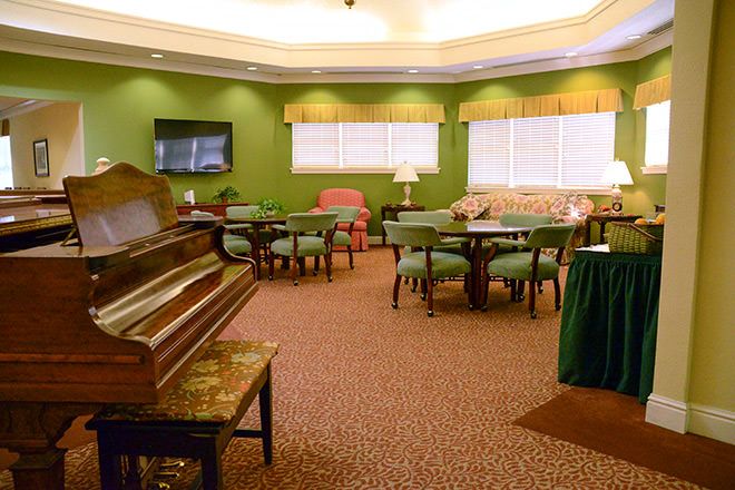 A cozy room with a piano, multiple seating areas, and a television.