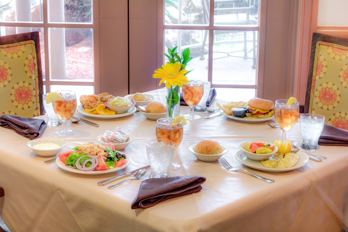 A beautifully set dining table with a variety of dishes and drinks, adorned with flowers.