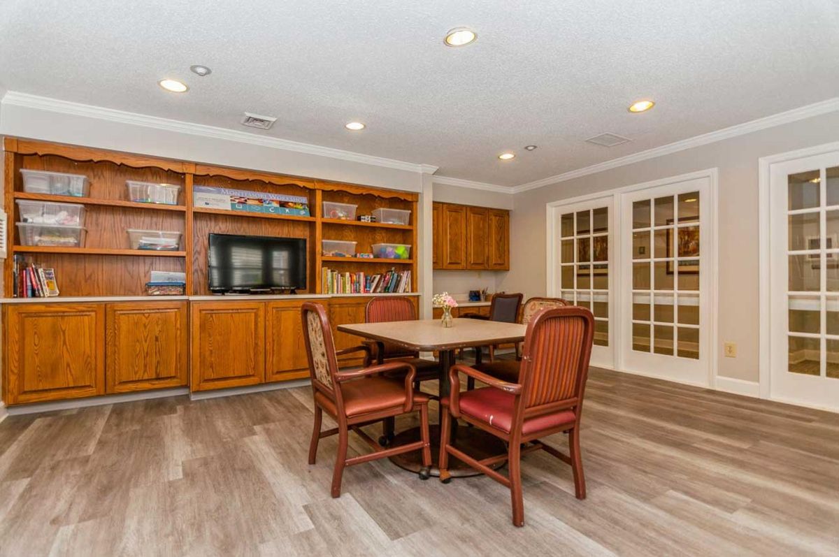 A cozy library meeting room with wooden bookshelves, table, and chairs.
