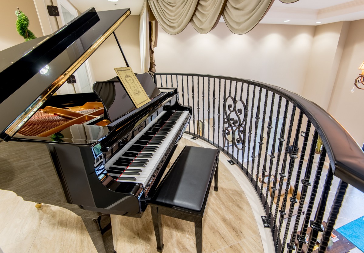 An elegant music room featuring a grand piano on a balcony.