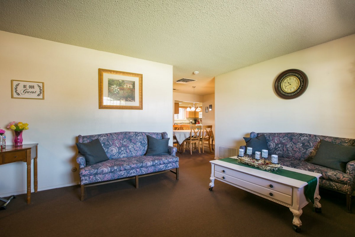 A cozy living room with a sofa, coffee table, and decorative elements like a painting and a wall clock.