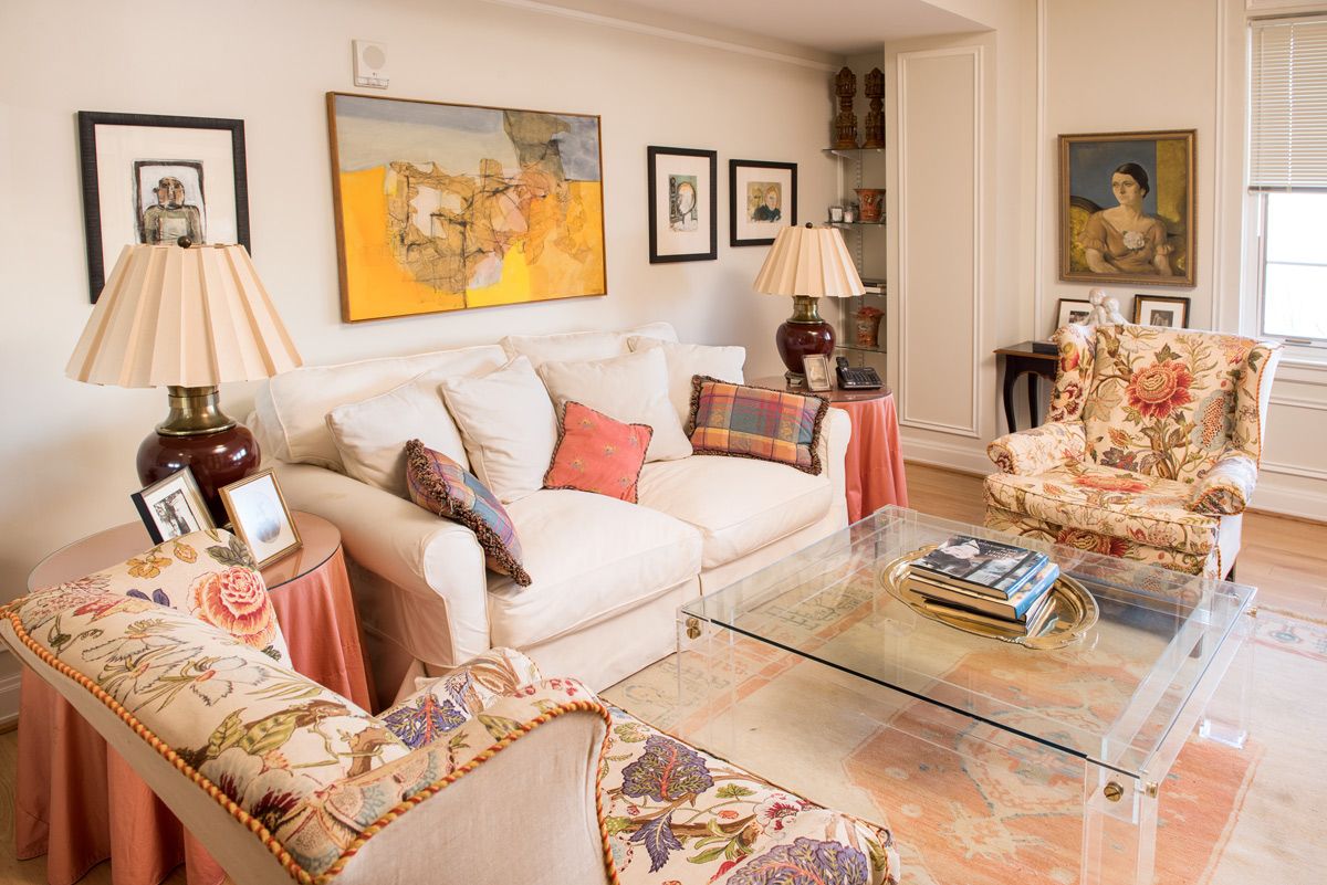 A cozy living room with a beige sofa, decorative pillows, and warm lighting. The space features colorful artwork and elegant furnishings.