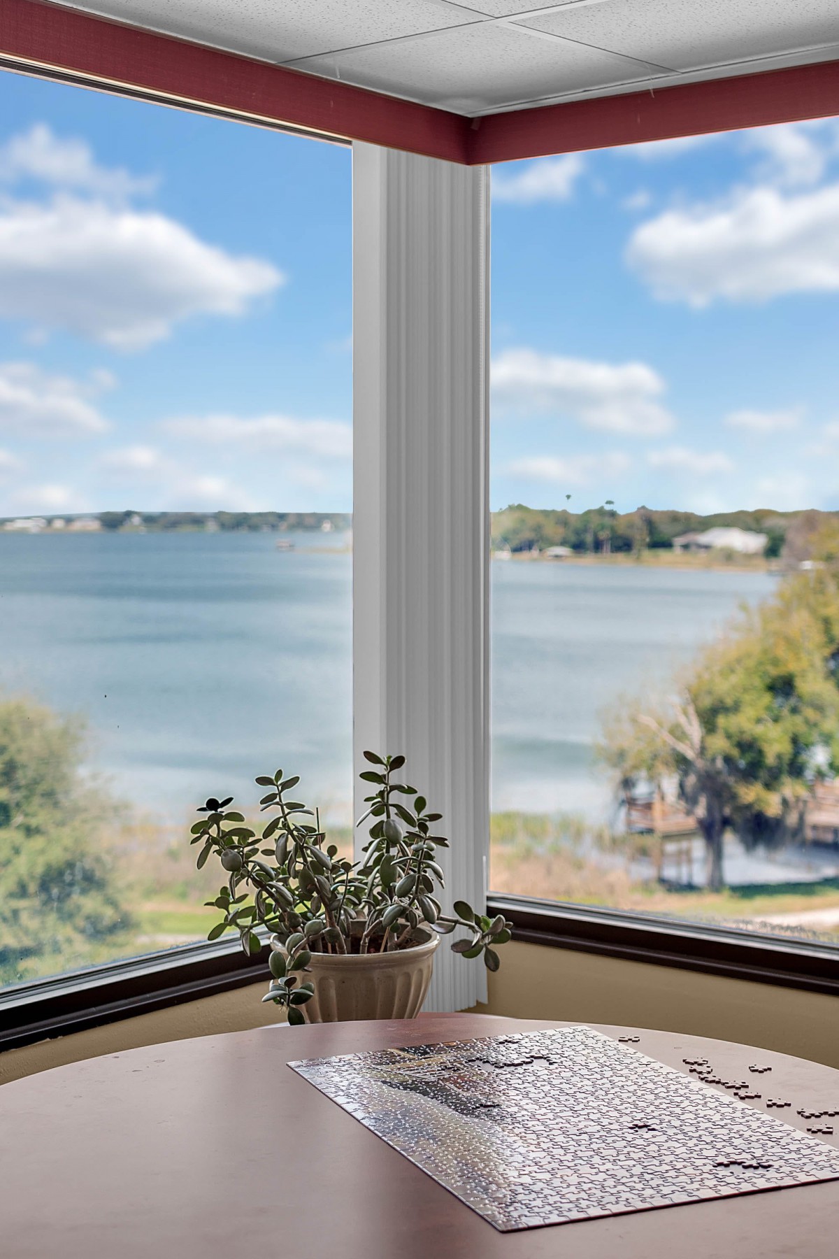 A serene lake view through a window with a potted plant in the foreground.