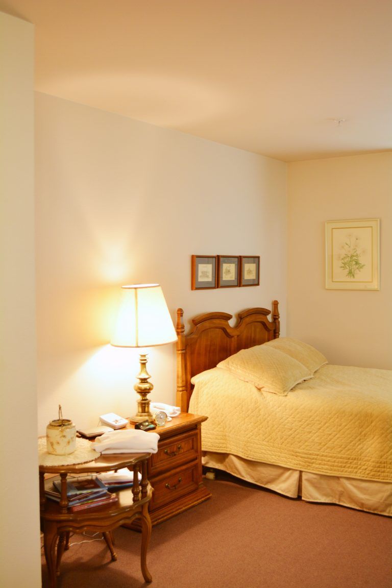 A cozy bedroom with a warmly lit lamp and neatly made bed.