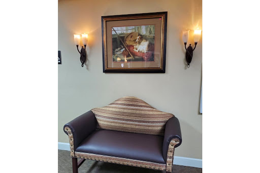 A cozy corner featuring a striped sofa and framed artwork, illuminated by stylish wall sconces.