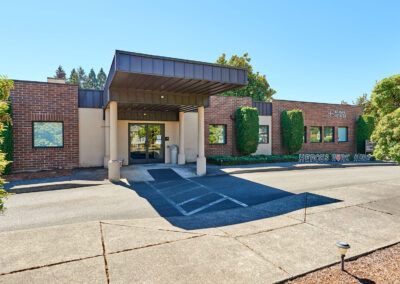 A brick office building with a covered entrance and parking area.