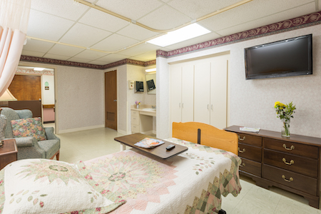A well-lit and spacious hospital room equipped with essential furniture for patient care.