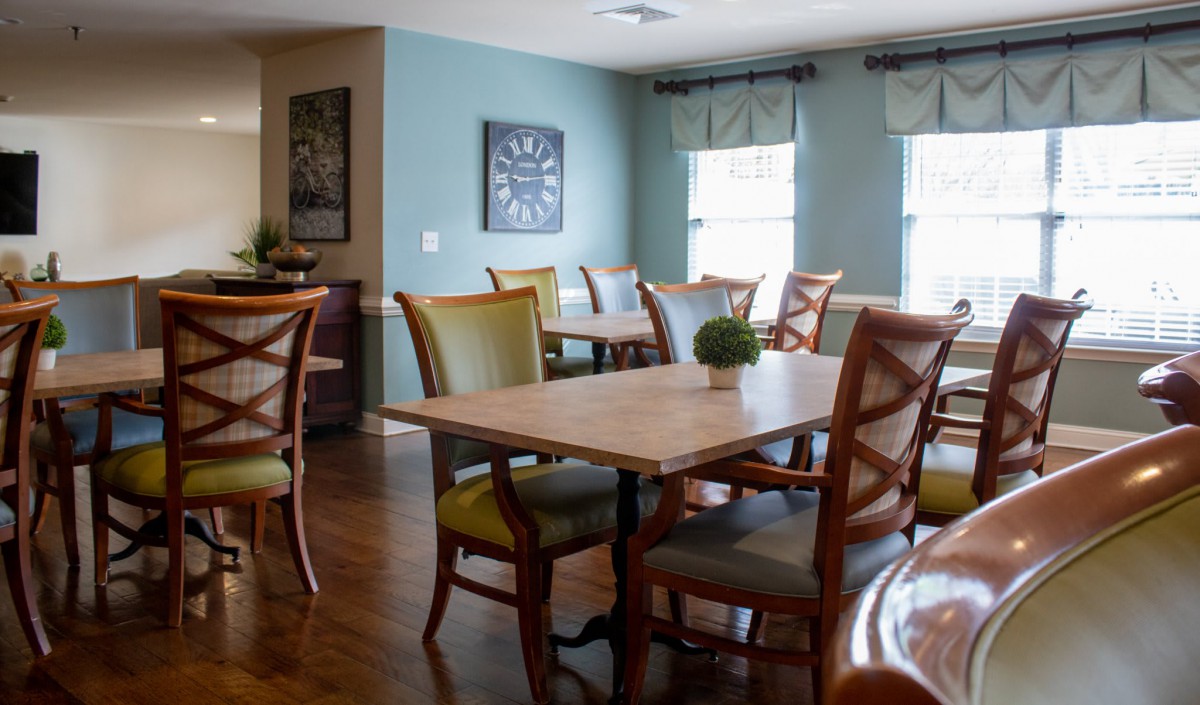 A cozy dining room with wooden tables and chairs, accented by decorative plants.