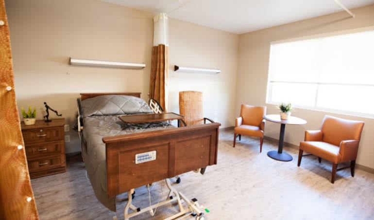 A clean and well-lit hospital room with a bed and seating area.