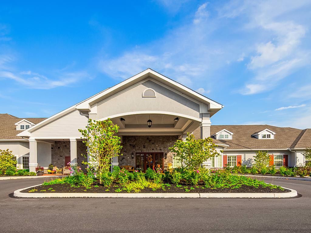 A beautiful building with a landscaped garden and welcoming entrance under a blue sky.